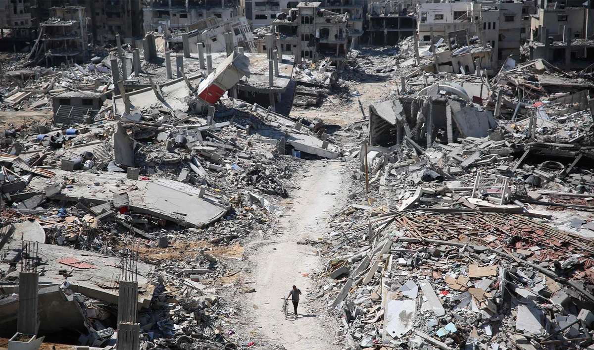 A man pushes a bycicle along as he walks amid building rubble in the devastated area around Gaza's Al-Shifa hospital on April 3, 2024. (AFP)