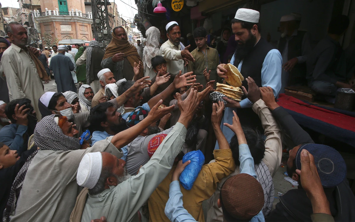 People receive free bread distributed by a volunteer for breaking their fast during the Muslim's holy fasting month of Ramadan outside a restaurant in Peshawar, Pakistan, on April 4, 2024. (AP)
