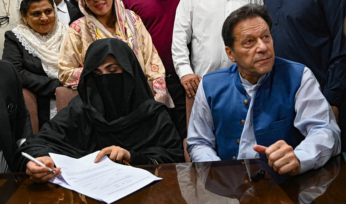 Pakistan's former Prime Minister, Imran Khan (R) along with his wife Bushra Bibi (L) looks on as he signs surety bonds for bail in various cases, at a registrar office in the High court, in Lahore on July 17, 2023. (AFP/File)