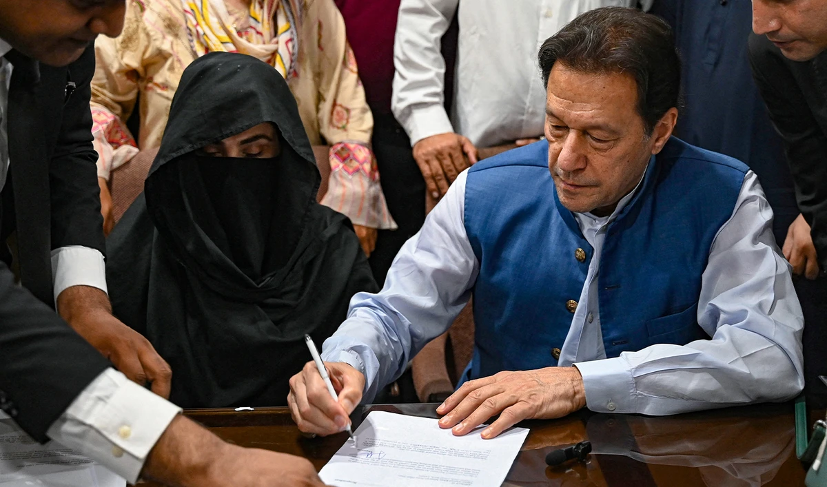 Pakistan's former Prime Minister, Imran Khan (R) along with his wife Bushra Bibi (C) signs surety bonds for bail in various cases, at a registrar office in the High court, in Lahore on July 17, 2023. (AFP/File)