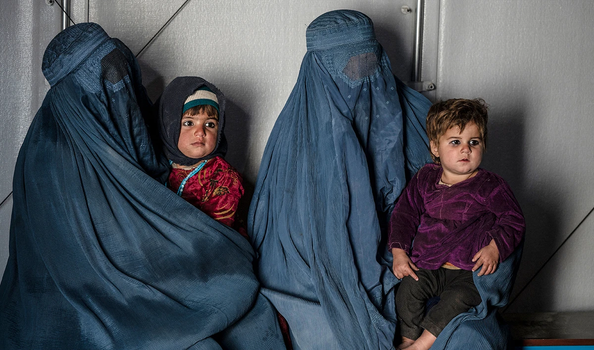 This photograph taken on January 9, 2024 shows Afghan burqa-clad women and children refugees deported from Pakistan, in a counselling room at the United Nations High Commissioner for Refugees (UNHCR) camp on the outskirts of Kabul. (AFP/File)