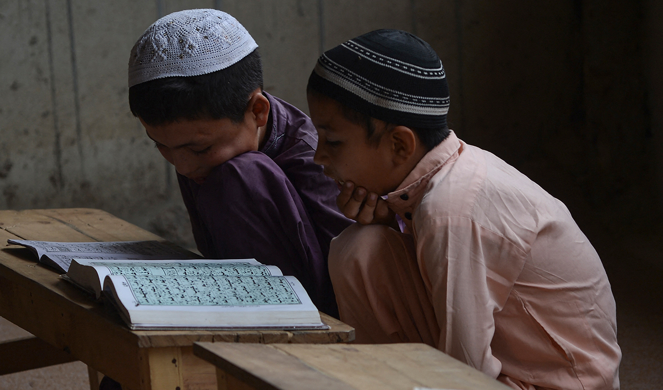 In this photo taken on September 21, 2023, Afghan boys read the Quran at an Afghan refugee camp in Karachi. (AFP/File)