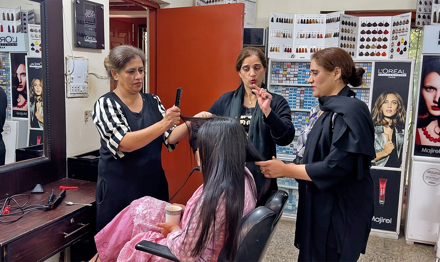 Staff at Options beauty salon interact with each other using sign language while styling a customer's hair on May 2, 2024, in Abbotabad, Pakistan. (AN Photo)