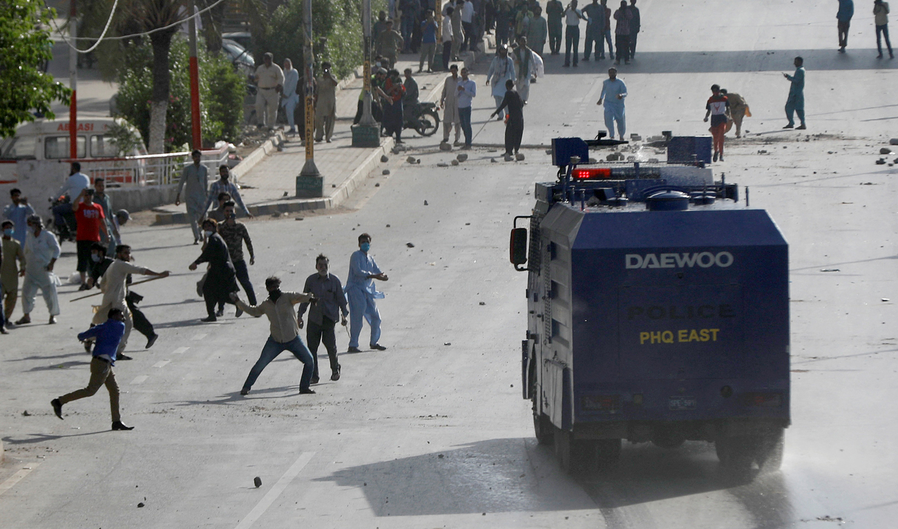 In this file photo, taken on May 9, 2023, supporters of Pakistan’s former Prime Minister Imran Khan throw stones at a police vehicle during a protest after Khan’s arrest, in Karachi. (REUTERS/File)