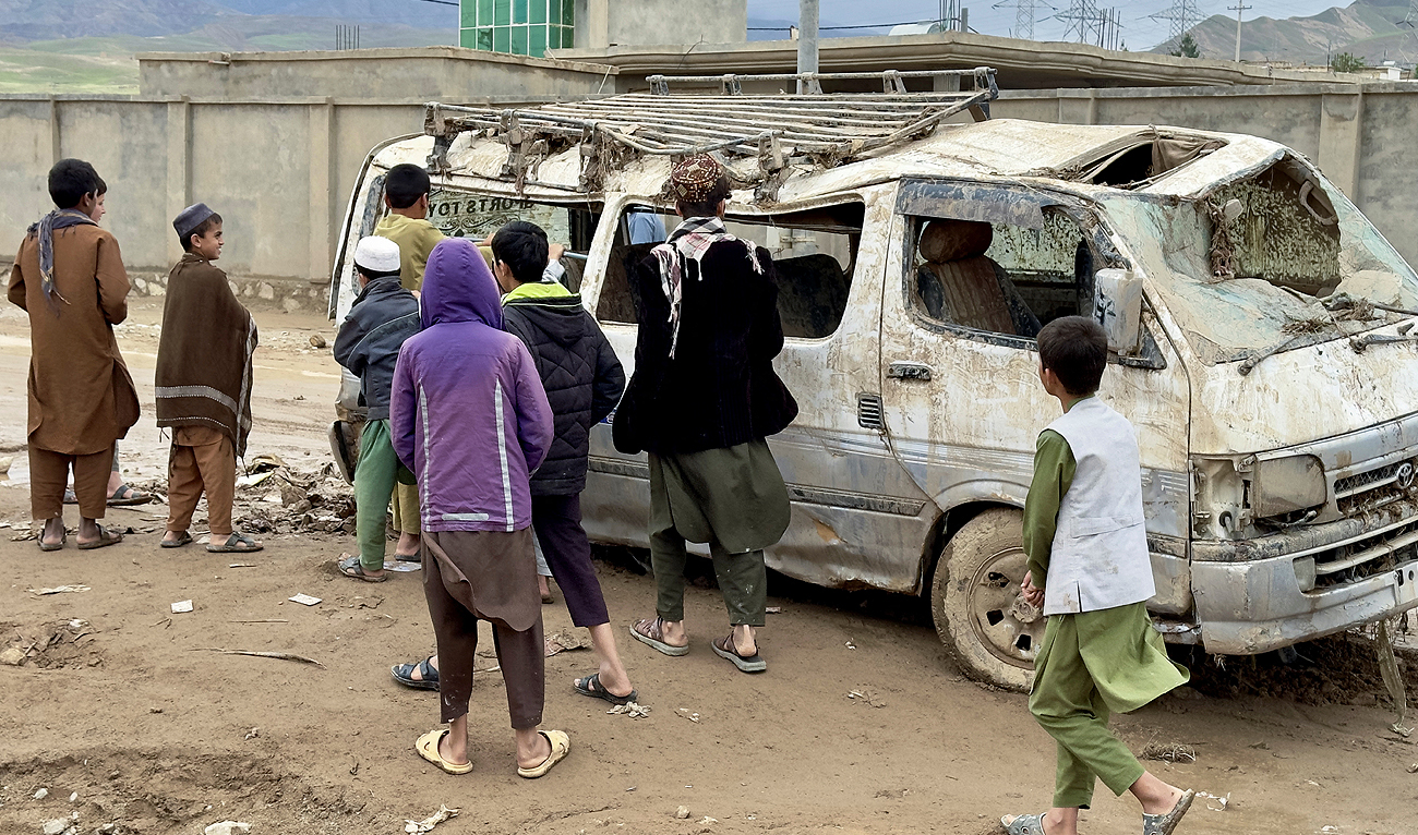 People look at a damaged vehicle, in the aftermath of floods following heavy rain, in Kar Kar village, Baghlan province, Afghanistan on May 11, 2024. (REUTERS)