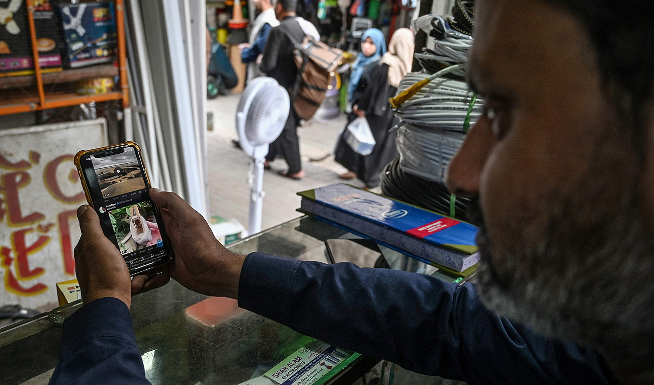 A man uses the social media platform X, formerly known as Twitter, on his phone at a market in Islamabad on April 17, 2024. (AFP)