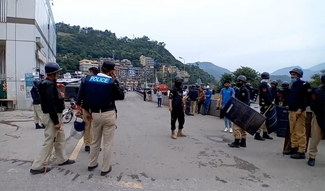 Police stand guard as supporters of the Jammu Kashmir Joint Awami Action Committee (JAAC) rights organization protest against electricity prices and subsidized wheat flour in Pakistan-administered Kashmir on May 12, 2024. (Syed Nadeem Shah/Independent Urdu)