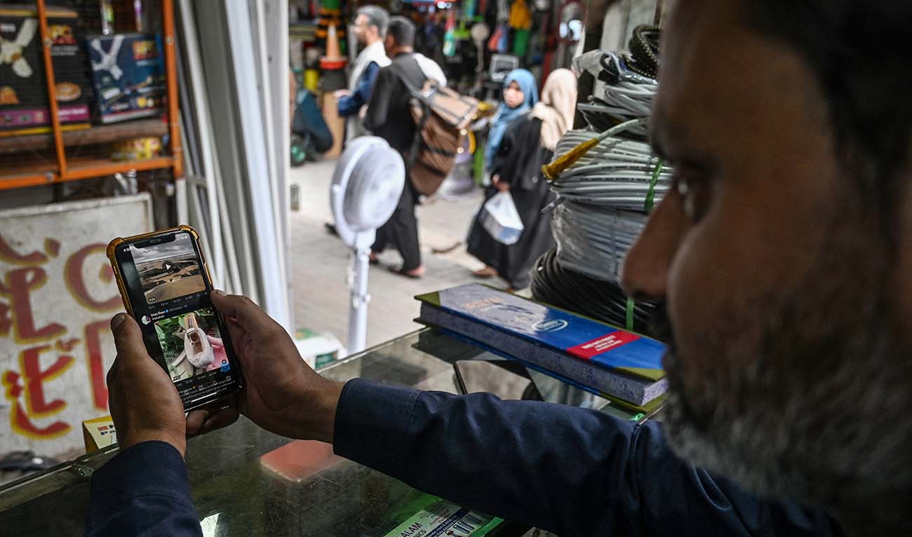 A man uses the social media platform X, formerly known as Twitter, on his phone at a market in Islamabad on April 17, 2024. (AFP/File)