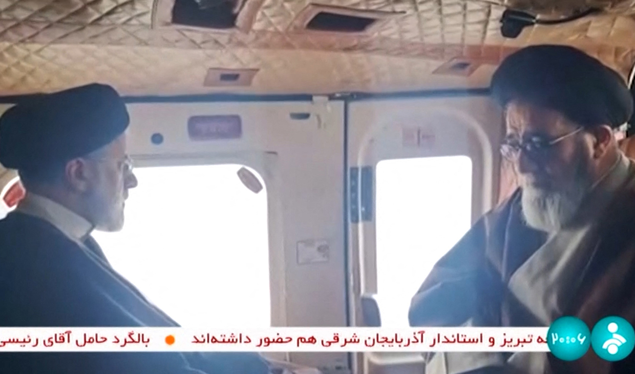 This grab taken from handout video footage released by the IRINN Iranian state television network on May 19, 2024 shows Iran's President Ebrahim Raisi (L) with an unidentified memeber of his delegation on board a helicopter in the Jofa region of the western province of East Azerbaijan. (AFP)
