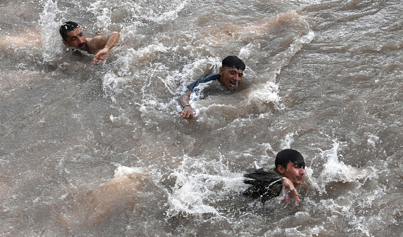 People swim in a canal to cool themselves during a hot summer day in Lahore on May 16, 2024. (FP)
