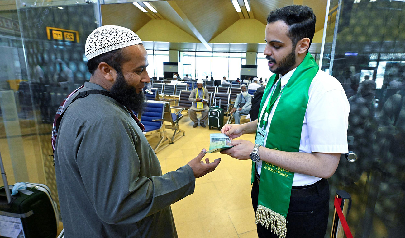 An official of Makkah Route checks the passport of a pilgrim at immigration as he leaves for Saudi Arabia for the annual Hajj pilgrimage from Pakistan on May 20, 2024. (SPA)
