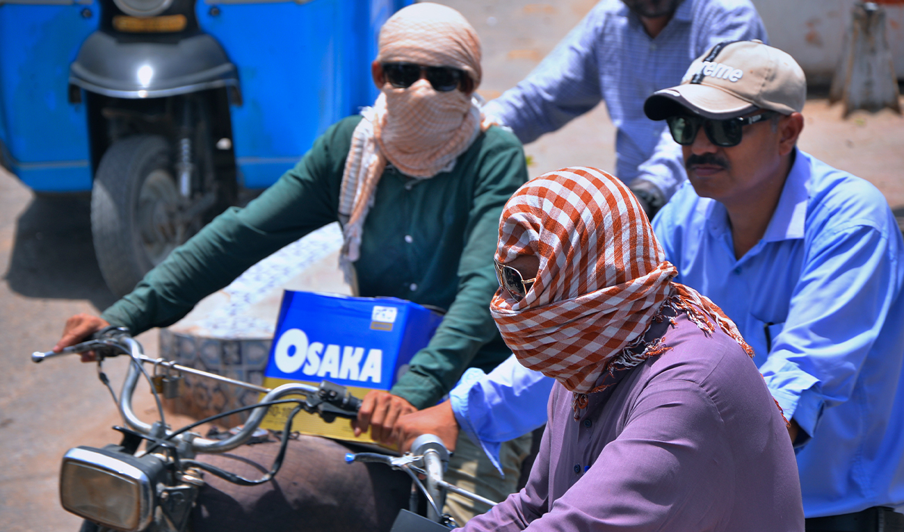 Motorcyclists cover their face with a scarf to protect themselves from heat as they travel on a road, in Hyderabad, Pakistan, on May 21, 2024. (P)