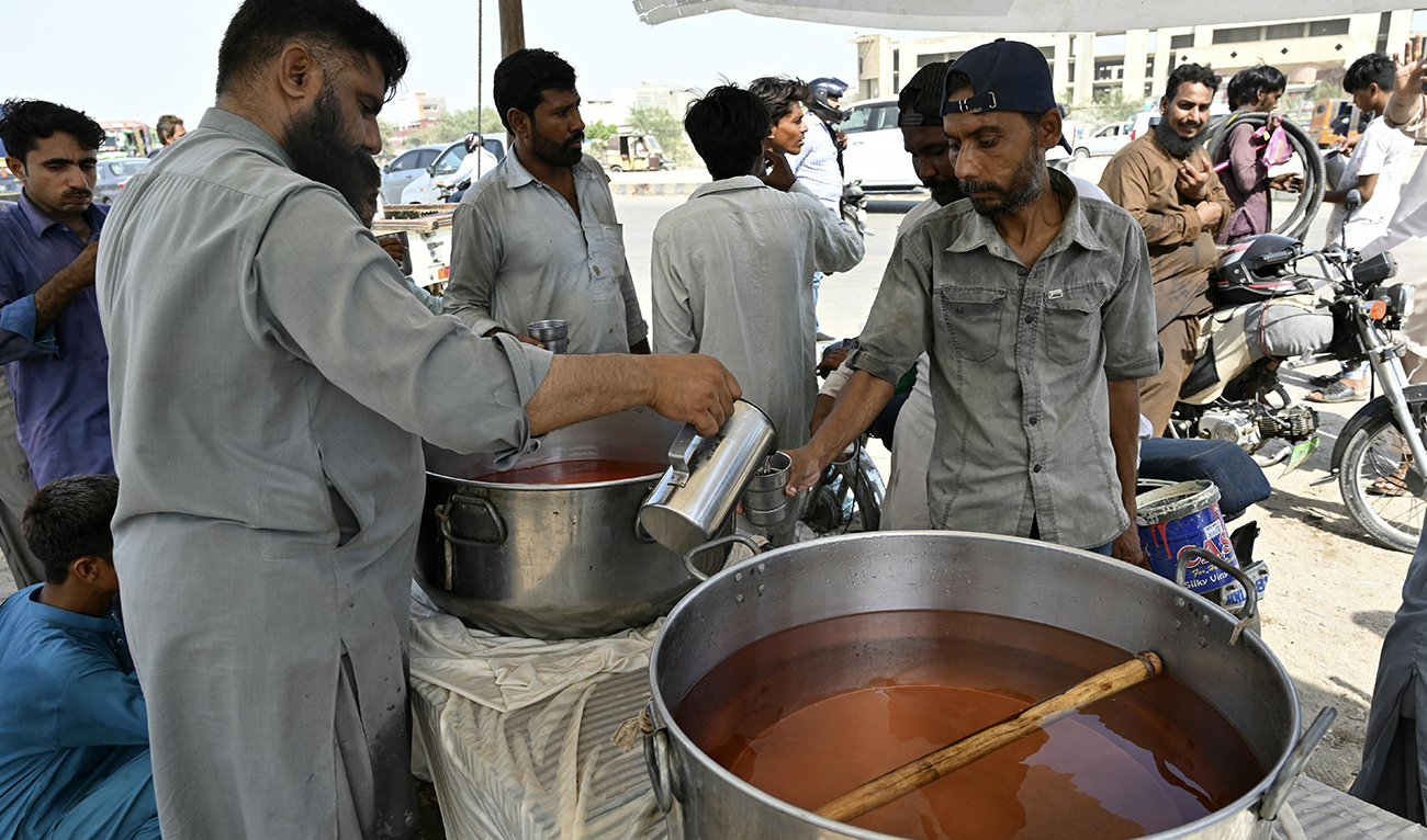A volunteer distributes chilled soft drinks to bypassers along a street amidst a heatwave in Karachi on May 21, 2024. (AFP)