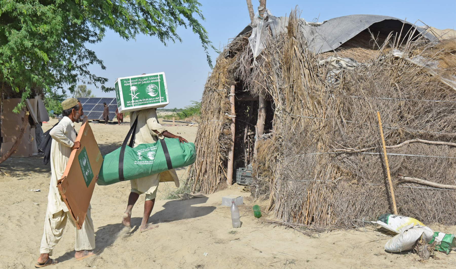 The picture shared by KSRelief on May 22, 2024, shows flood-affectees carrying shelter and non-food items distributed by King Salman Humanitarian Aid and Relief Center (KSRelief) in Pakistan. (KSRelief)