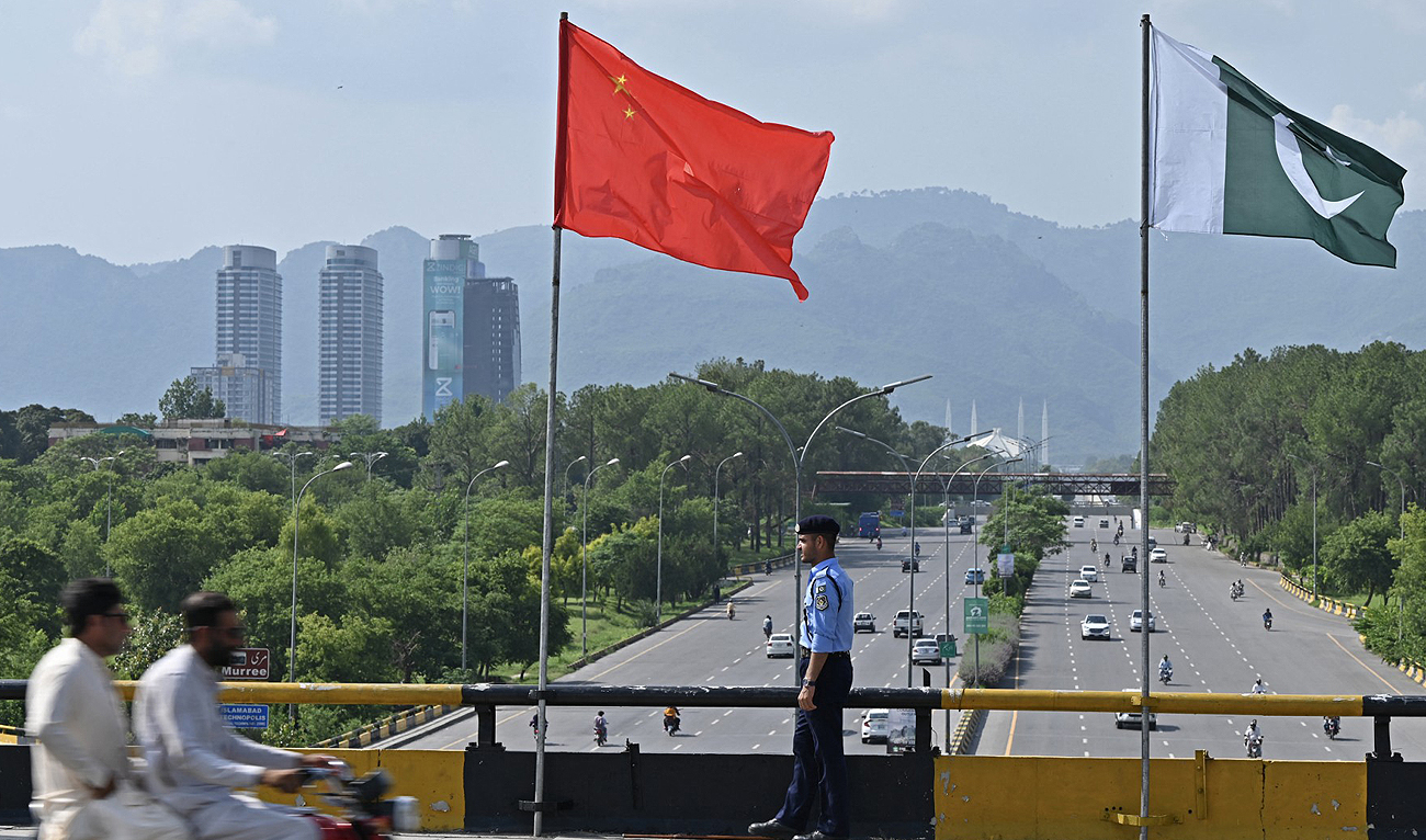 A policeman stands guard under the national flags of China and Pakistan along a road ahead of the visit of Chinese Vice Premier He Lifeng, in Islamabad on July 30, 2023. (AFP/File)