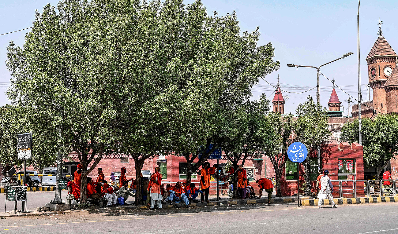Porters sit under a tree as they wait for passengers on a hot summer day outside the Lahore railway station in Lahore on May 22, 2024. (AFP)