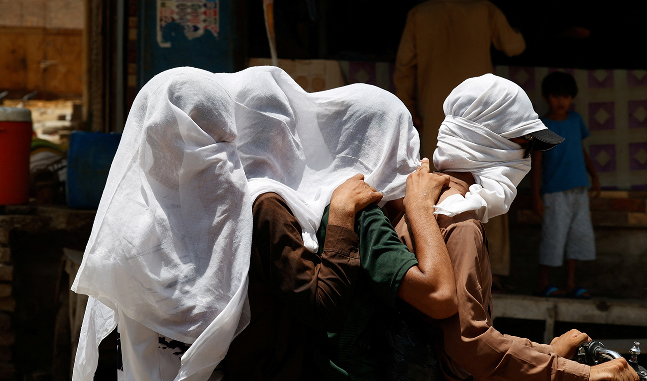 Men ride on a motorbike as they cover their heads with a wet cloth to cool off and to avoid sunlight, during a hot summer day, as the heatwave continues in Jacobabad, Pakistan May 26, 2024. (Reuters)