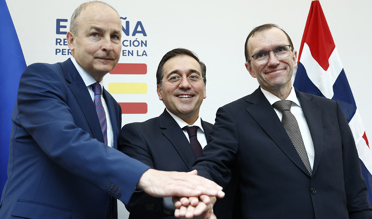 Spanish Minister for Foreign Affairs, European Union and Cooperation, Jose Manuel Albares (C), Norwegian Foreign Minister Espen Barth Eide (R) and Irish Foreign minister Micheal Martin join hands after holding a joint press conference at the the Permanent Representation of Spain to the European Union in Brussels on May 27, 2024. (AFP)