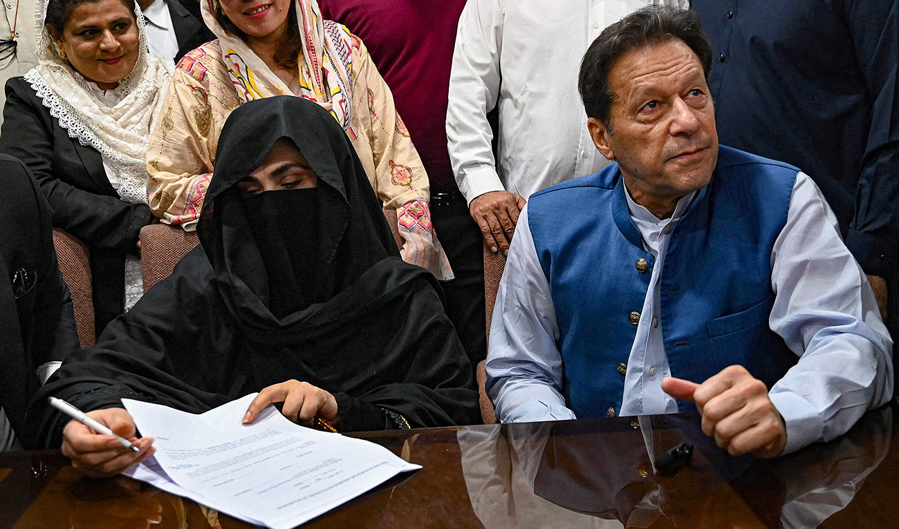 Pakistan's former Prime Minister, Imran Khan (R) along with his wife Bushra Bibi (L) looks on as he signs surety bonds for bail in various cases, at a registrar office in the High court, in Lahore on July 17, 2023. (AFP/File)