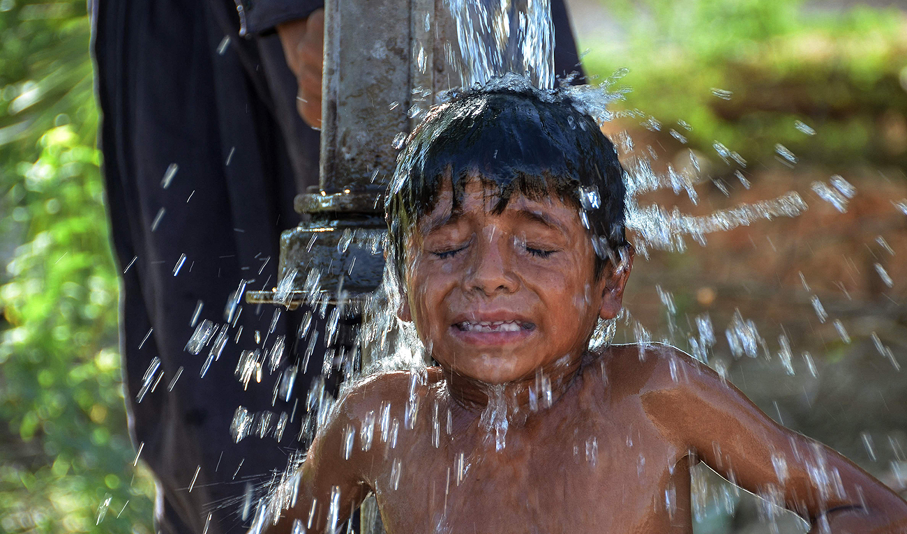 A boy takes bath under a hand pump during a hot summer day in Jaffarabad, in Pakistan's Balochistan province on May 29, 2024, amid the ongoing heatwave. (AFP)