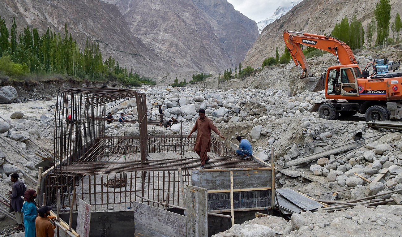 In this file picture taken on June 9, 2022, construction workers build a temporary bridge after a lake outburst because of a melting glacier swept away the main bridge in Hassanabad village of Pakistan’s Gilgit-Baltistan region. (AFP/File)