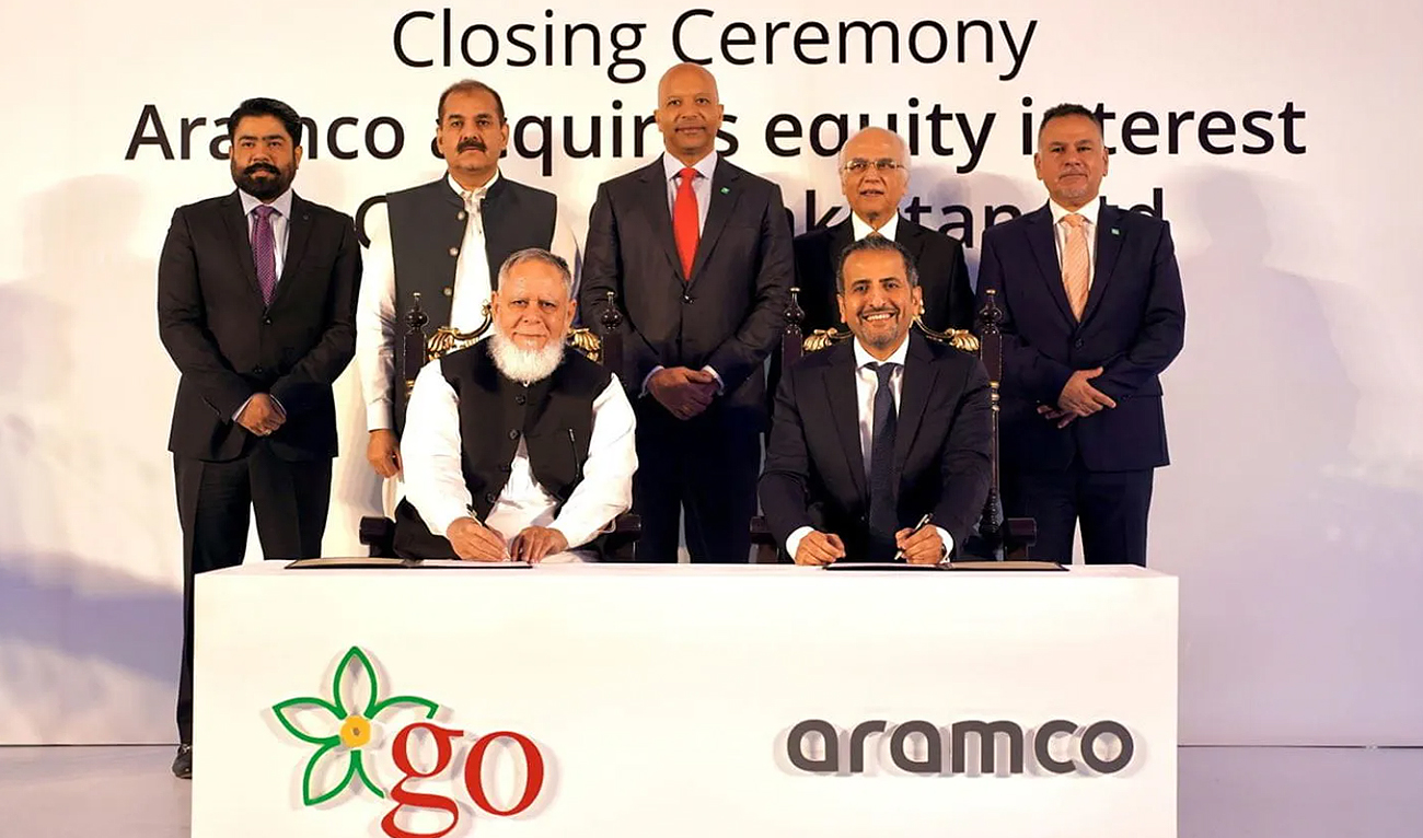 In this handout photograph, taken and released by Saudi Aramco, GO CEO Khalid Riaz (sitting left) and Aramco Director of International Retail Nader Douhan (sitting right) signing papers at the closing ceremony of an acquisition deal in Riyadh on May 31, 2024. (Photo courtesy: Saudi Aramco)