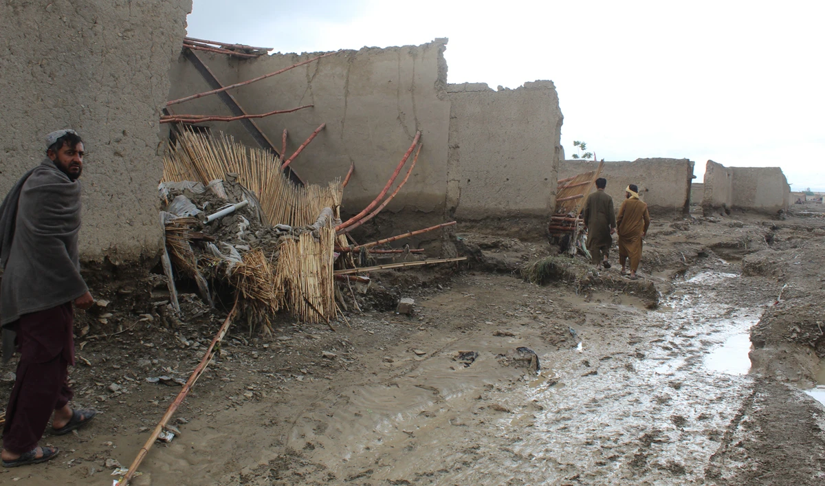 Residents walk past damaged houses after heavy rains on the outskirts of Chaman in Balochistan province on April 19, 2024. (AFP)