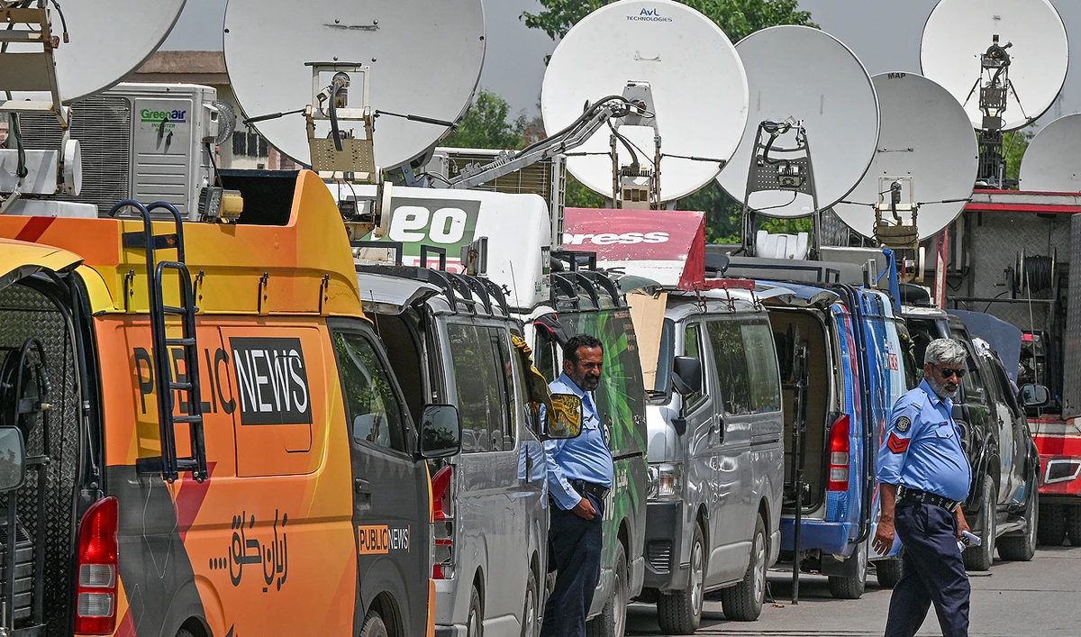 Police personnel stand guard in front of news media vans parked outside a special court in Islamabad on August 21, 2023. (AFP/File)