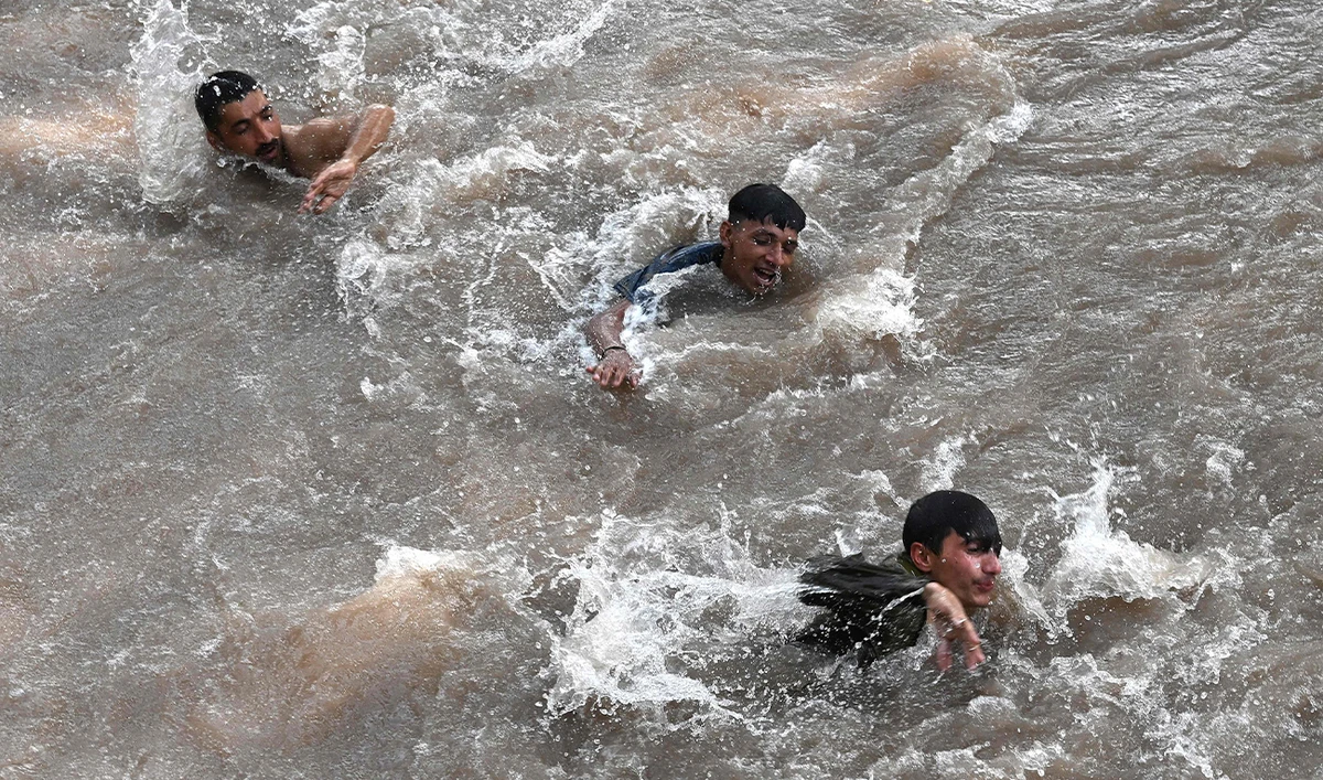 People swim in a canal to cool themselves during a hot summer day in Lahore on May 16, 2024. (FP)