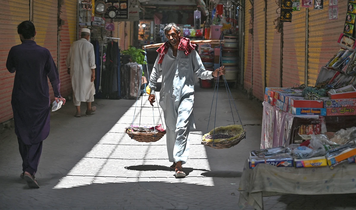 A street vendor selling phalsa fruits looks for customers along a market in Rawalpindi on June 9, 2023. (AFP/File)