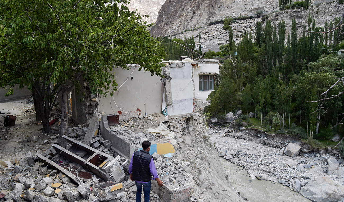 In this picture taken on June 9, 2022, a local resident stands beside his damaged house after it was swept by a lake outburst because of a melting glacier, in Hassanabad village of Pakistan's Gilgit-Baltistan region. (AFP/File)