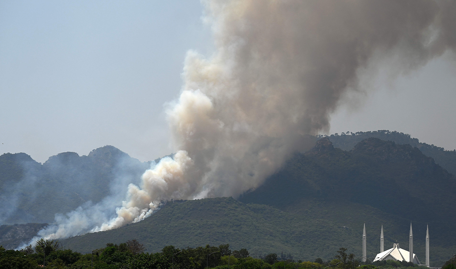 Smoke rises from a fire that erupted few days back in Margalla Hills forest near Faisal Mosque amid rising temperatures during a hot summer day in Islamabad on May 31, 2024. (AFP)