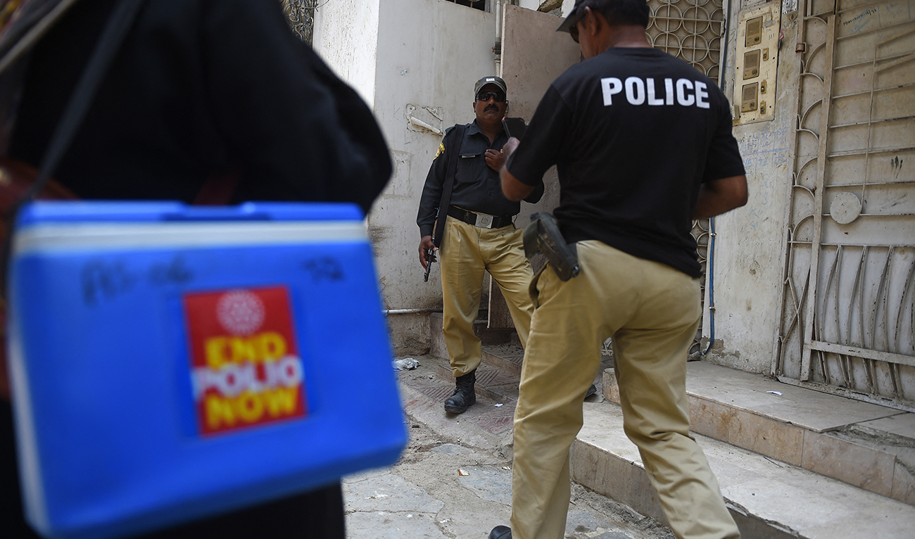 Policemen escort members of a polio vaccination team during a door-to-door vaccination campaign in Karachi on June 28, 2022. (AFP/File)