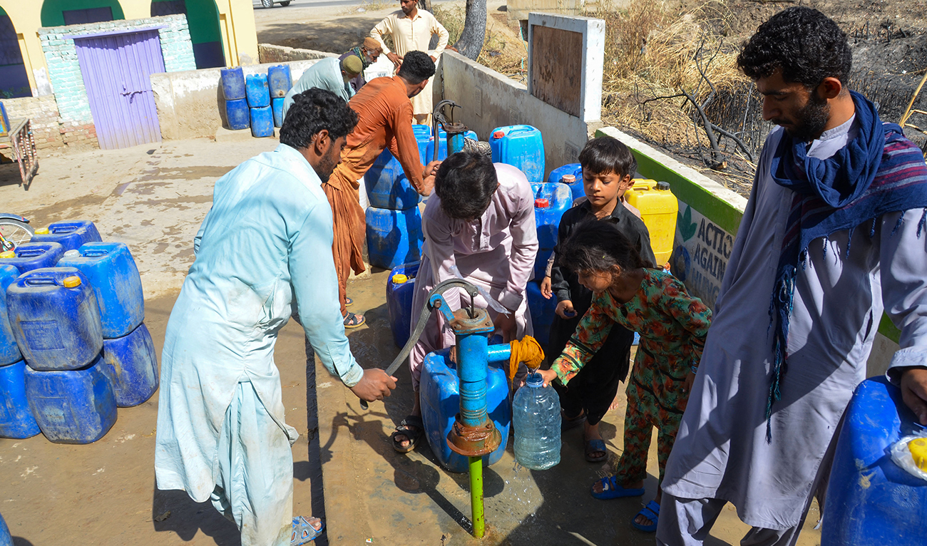 People fill cans with water from a hand pump on a hot summer day in Jaffarabad, in Pakistan's Balochistan province on May 31, 2024, amid the ongoing heatwave. (AFP/File)