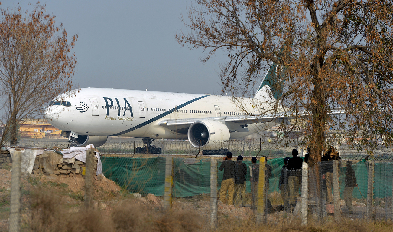 Pakistan policemen stand guard as a Pakistan International Airline (PIA) plane taxis on the runway on the way to Saudi Arabia during the PIA employees strike in Islamabad on February 8, 2016. (AFP/File)
