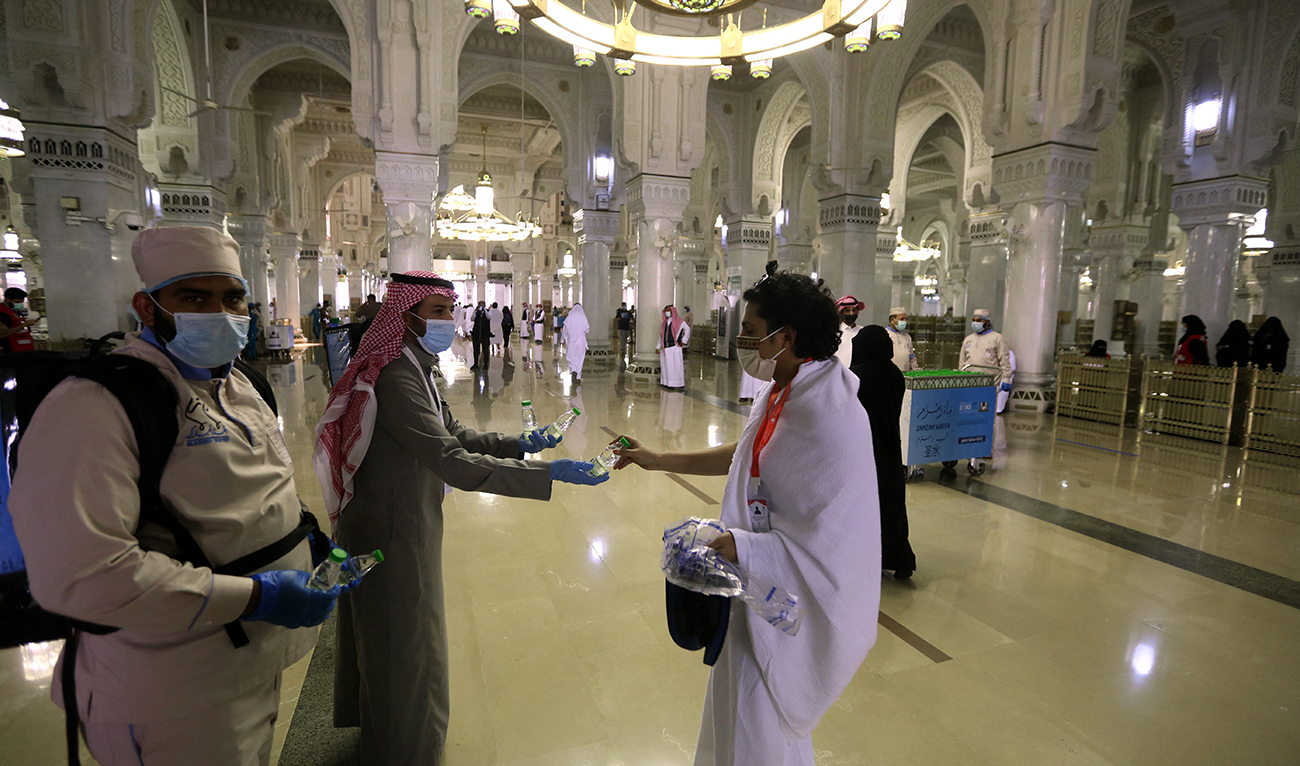 A man hands a bottle of water to a pilgrim at the Grand mosque in the holy city of Meccca, at the start of the Hajj season, on July 17, 2021. (AFP/File)