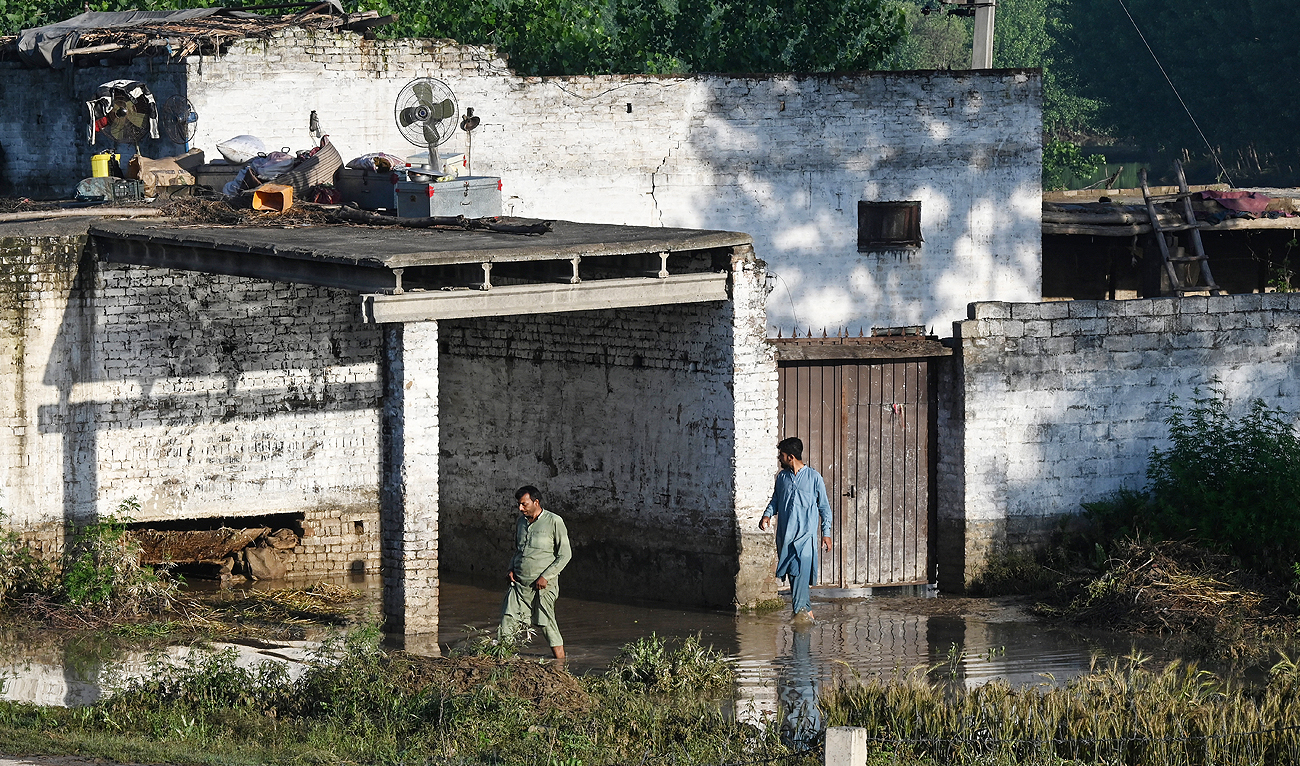 Residents wade through the flooded waters outside their homes following heavy rains in Charsadda district of Khyber Pakhtunkhwa province on April 17, 2024. (AFP)