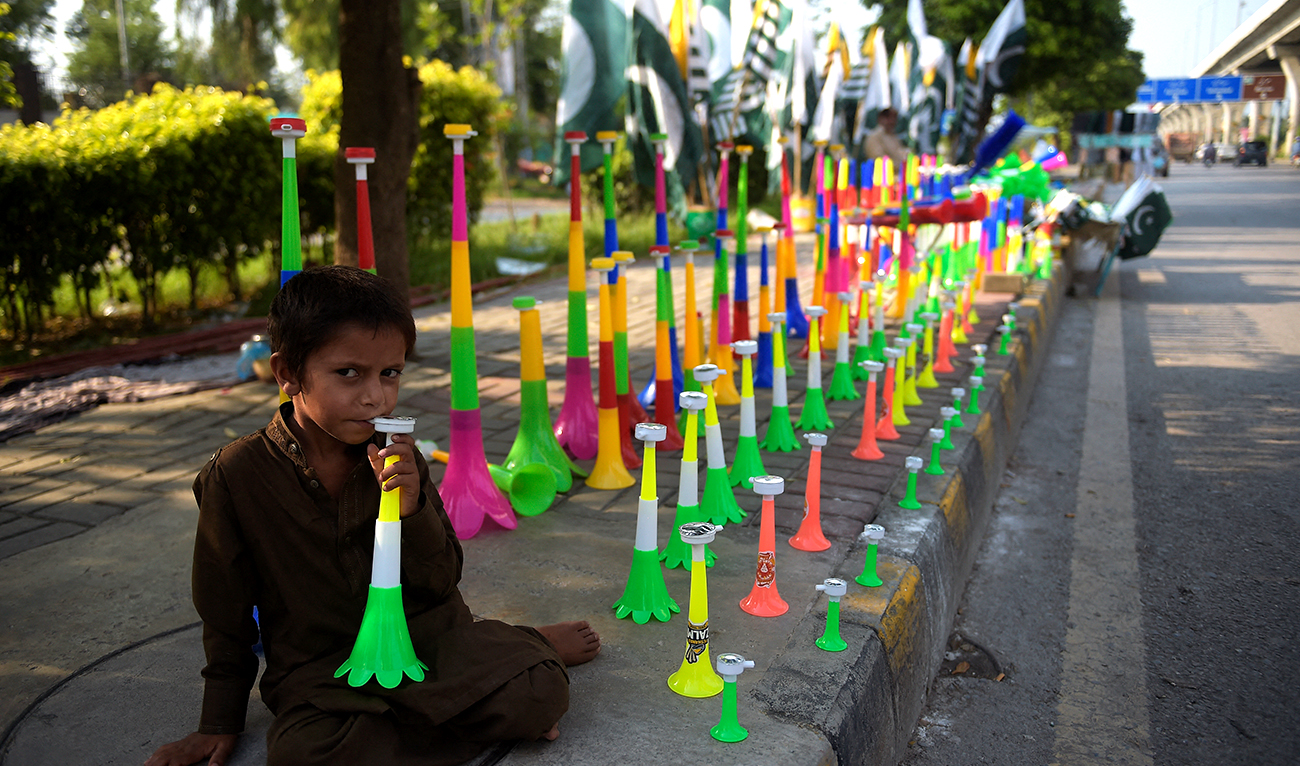 A boy selling plastic horns waits for customers on a roadside stall in Rawalpindi on August 4, 2020, ahead of Pakistan's 74th anniversary of independence from British rule. (AFP/File)