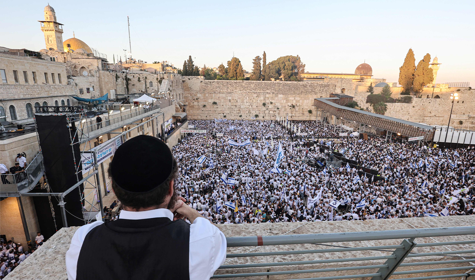 A man looks down on hundreds of Israeli nationalists, including far-right activists, gather at the Western Wall in the Old City of Jerusalem on June 5, 2024, during the so-called Jerusalem Day flag march which commemorates the Israeli army's capture in the 1967 Arab-Israeli war of the city's eastern sector home to the Al-Aqsa mosque compound, Islam's third holiest site, which Jews call the Temple Mount. (AFP)