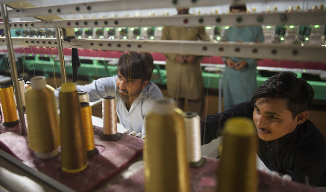 This file photo, taken on September 2, 2020, shows workers supervising embroidery machines working on fabrics for wedding dresses at a small factory on the outskirts of Islamabad. (AFP/File)