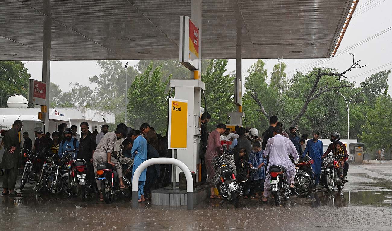 Commuters take shelter under a fuel station to protect themselves during rainfall in Islamabad on July 14, 2023. (AFP/File)