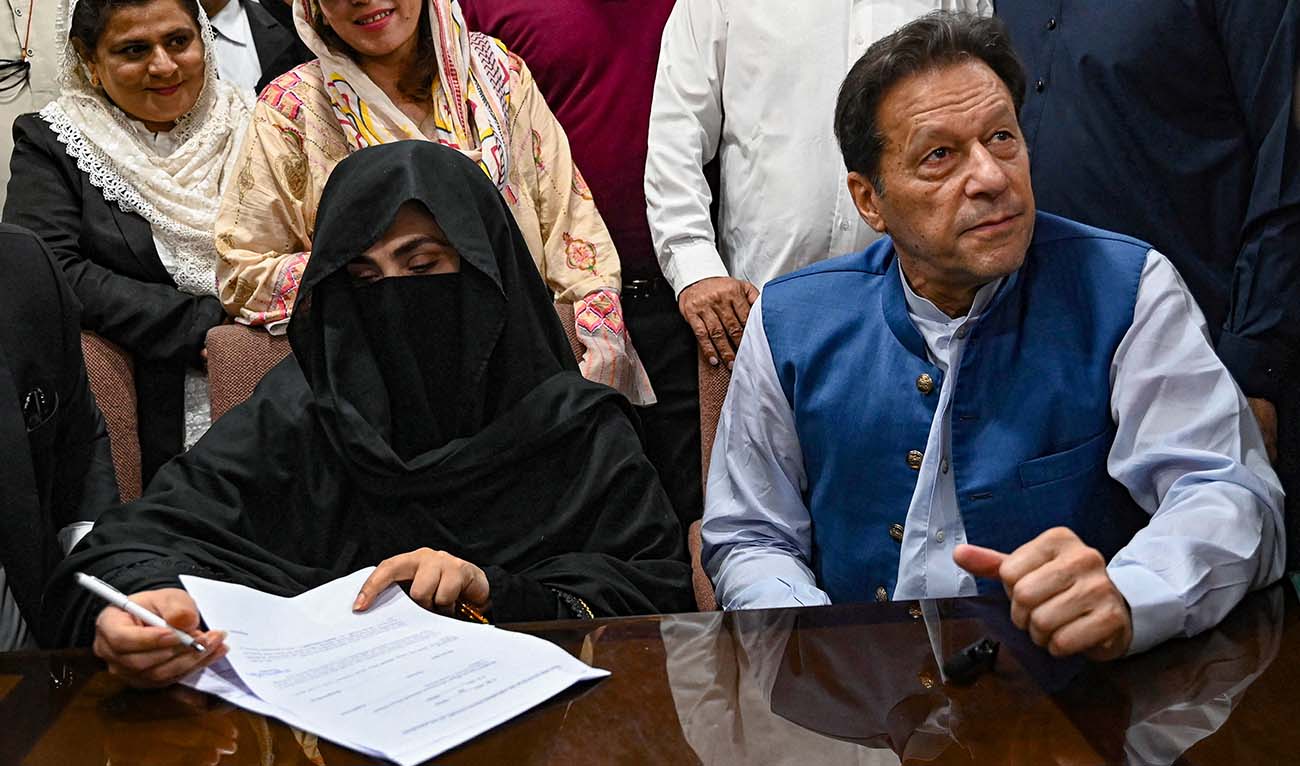 Pakistan's former Prime Minister, Imran Khan (R) along with his wife Bushra Bibi (L) looks on as he signs surety bonds for bail in various cases, at a registrar office in the High court, in Lahore on July 17, 2023. (AFP/File)