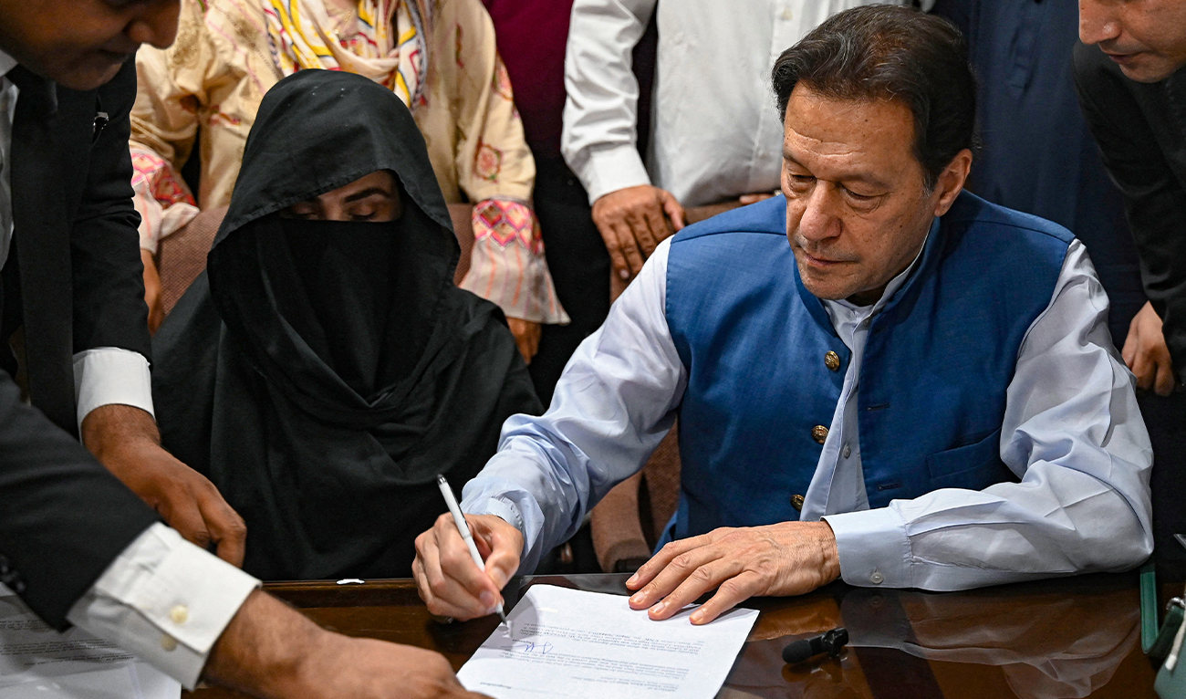 Pakistan's former Prime Minister, Imran Khan (R) along with his wife Bushra Bibi (L) looks on as he signs surety bonds for bail in various cases, at a registrar office in the High court, in Lahore on July 17, 2023. (AFP/File)