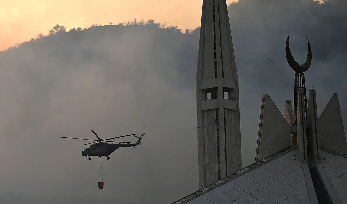 A Pakistan's military helicopter carrying water try to extinguish a fire that erupted few days back in Margalla Hills forest near Faisal Mosque amid rising temperatures during a hot summer day in Islamabad on May 31, 2024. (AFP)