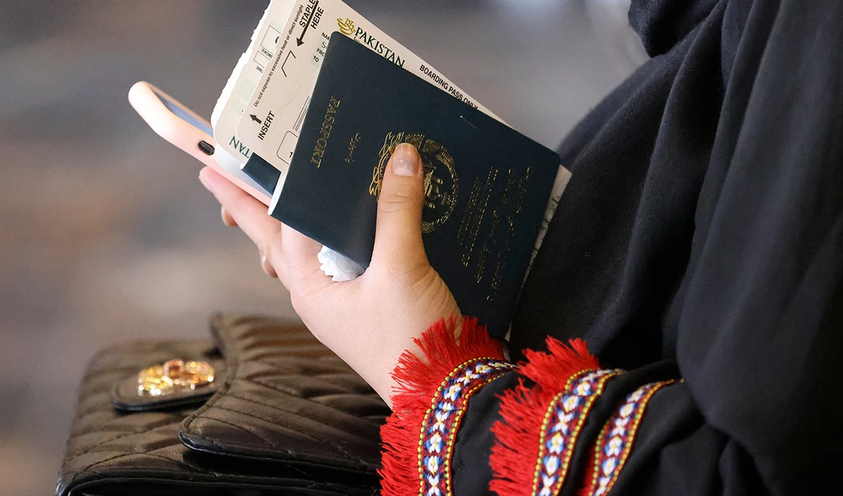 A woman holds her passport while sitting in a waiting room before boarding on a Pakistan International Airlines plane, the first commercial international flight to land since the Taliban retook power last month, at the airport in Kabul on September 13, 2021. (AFP)