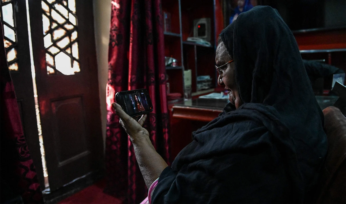 This photograph taken on May 16, 2024 shows Shagufta, a former sex worker with a pseudonym, watching the trailer of "Heeramandi", a Netflix series, on a mobile phone in the royal neighbourhood of Heera Mandi, a red-light zone, in Lahore. (AFP)