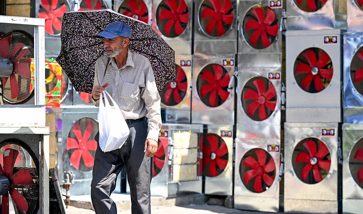 A customer carrying an umbrella visits a shop selling air coolers on a hot summer afternoon, at a market in Rawalpindi on May 30, 2024 amid the ongoing heatwave. (AFP/File)