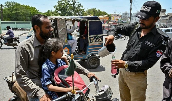A policeman distribute cold drinks to bypassers near a 'heatwave relief camp' during a hot summer day in Karachi on May 23, 2024. (AFP)