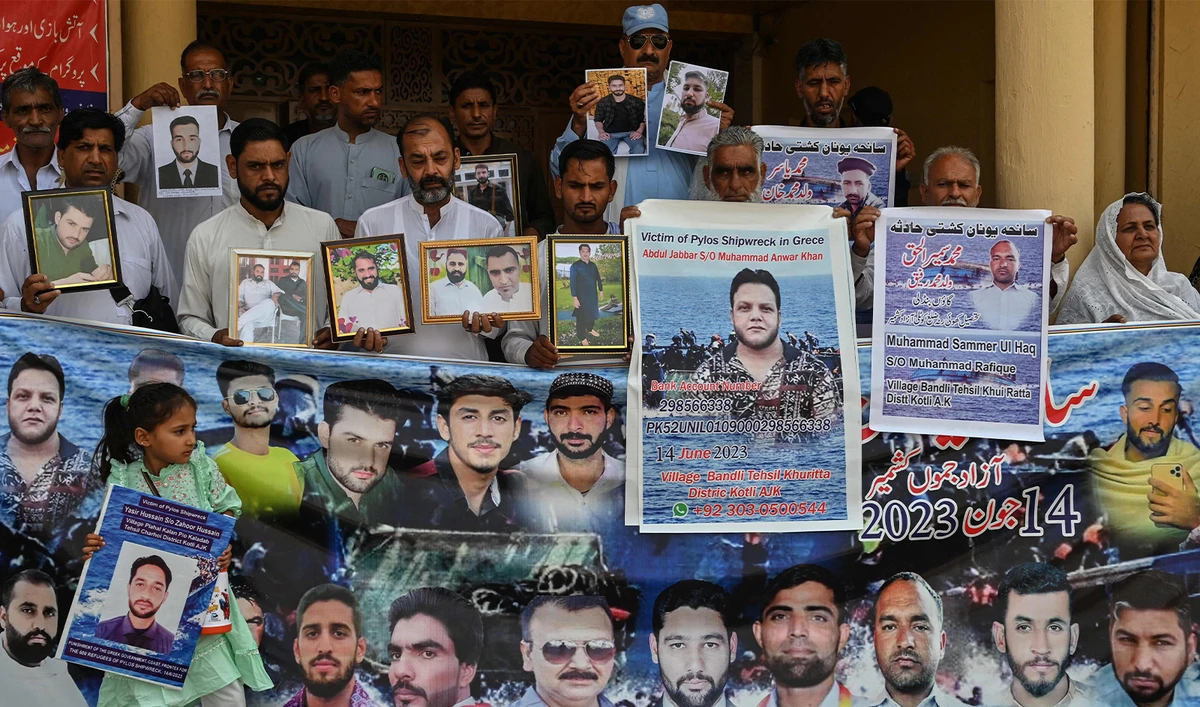 Family members hold photos of the victims of last year's Greece shipwreck tragedy as they gather to mark its first anniversary, in Lalamusa a town in Punjab province on June 14, 2024. (AFP)