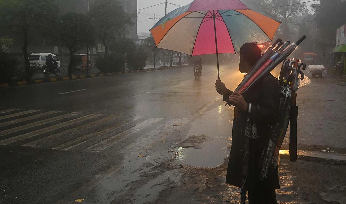 A street vendor carries umbrellas as he waits for customers along a road during a rain shower in Lahore on January 19, 2022. (AFP/File)